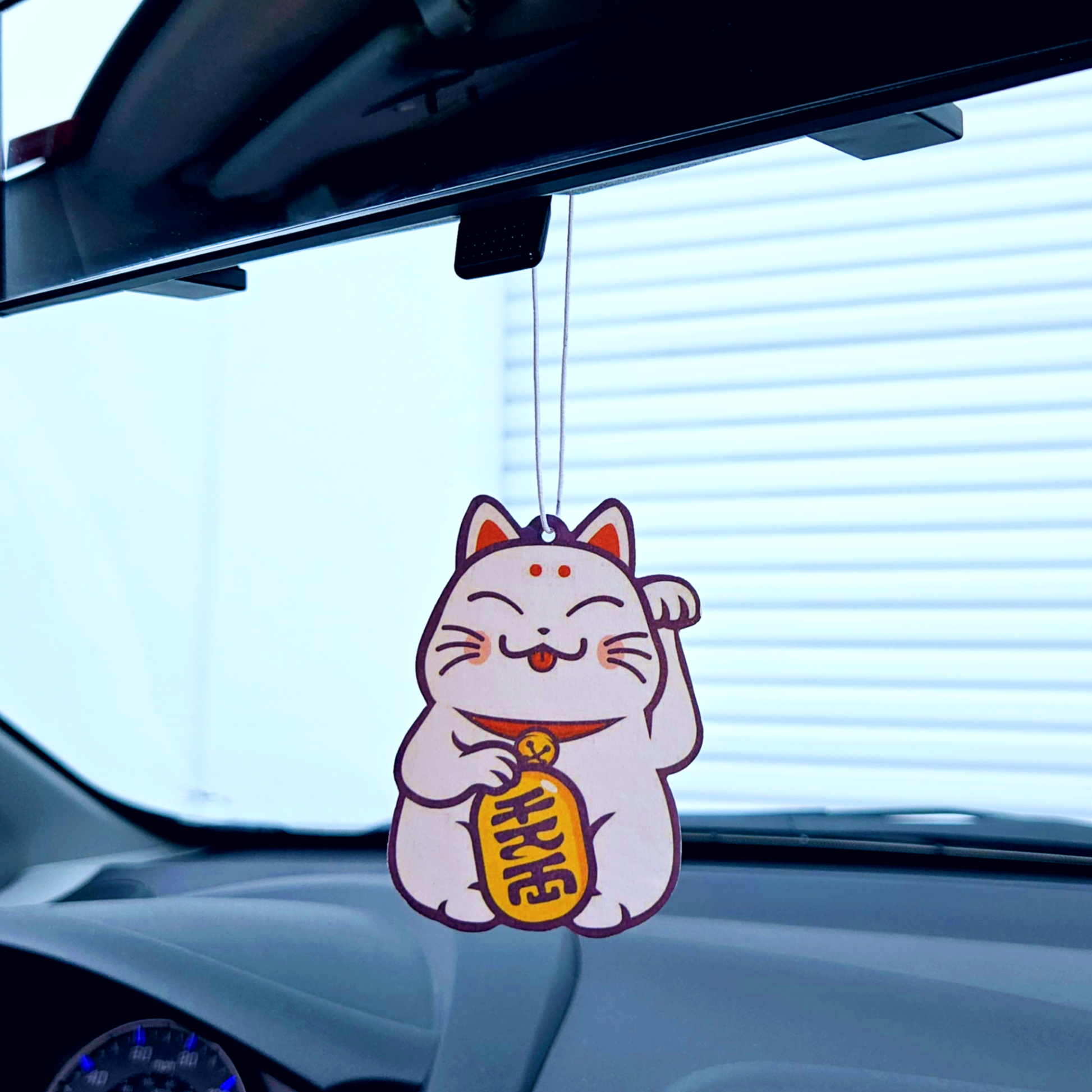 lucky cat air freshener hanging in rear view mirror